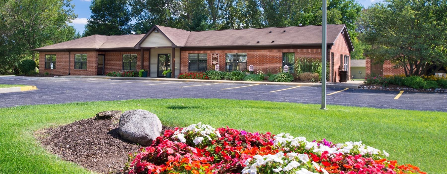 a building with a large lawn and flowers in front of it